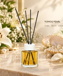 Odorizant Yumoş Pearl 120 ml cu flacon auriu și patru bețișoare negre, în decor elegant cu flori albe, perle și scoică decorativă.